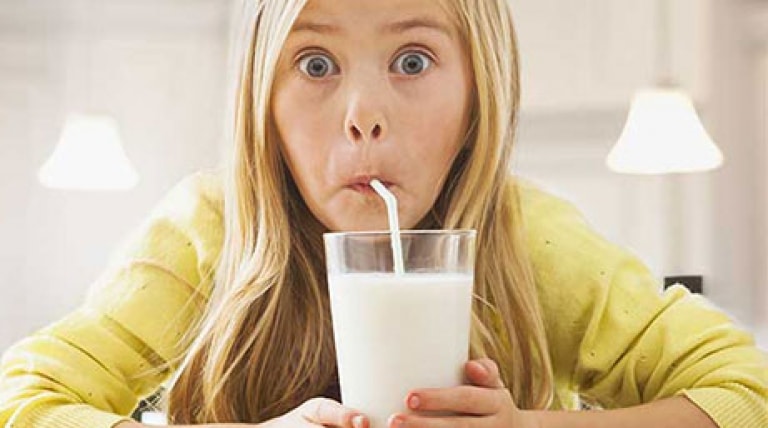 Girl drinking a glass of milk with a straw